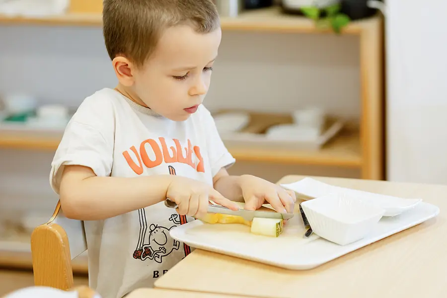 Niño en ambiente Montessori preparandose su snack. Rutina diaria que transforma una tarea cotidiana en un hito de autonomía.