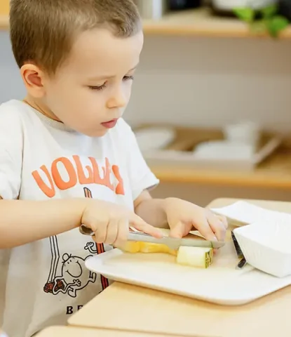 Niño en ambiente Montessori preparandose su snack. Rutina diaria que transforma una tarea cotidiana en un hito de autonomía.